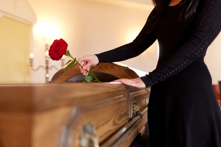 Una donna inserisce una rosa rossa dentro una bara